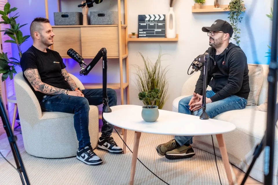 Két résztvevő podcast-beszélgetése a Skandináv stúdió kanapéján, az asztalon növénnyel