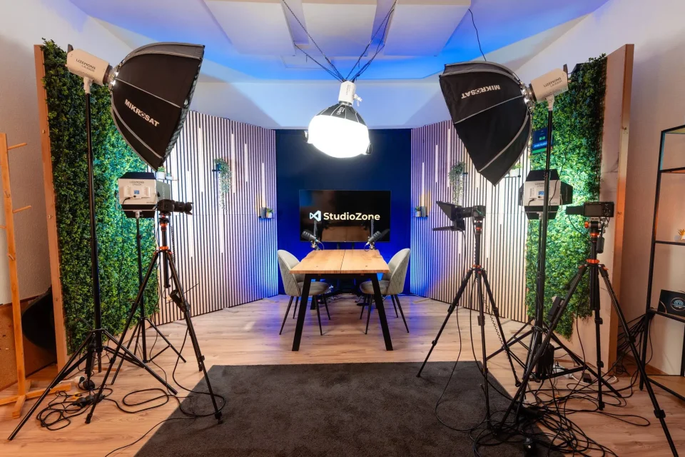 Zóne stúdió tágas belső tere két softbox lámpával, kamerákkal állványon és StudioZone logós háttérrel
