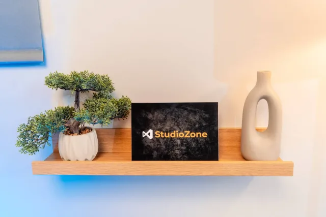 StudioZone márkás dekorpolc bonsaijjal, névjegykártyával és fehér vázával