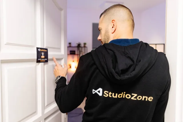 StudioZone feliratos pulóvert viselő férfi a podcast stúdió bejárati ajtajánál