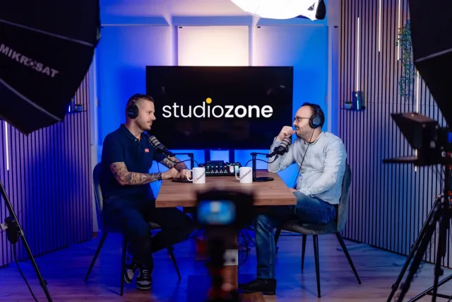 Két műsorvezető fejhallgatóban podcastot vesz fel, háttérben a studiozone kijelző
