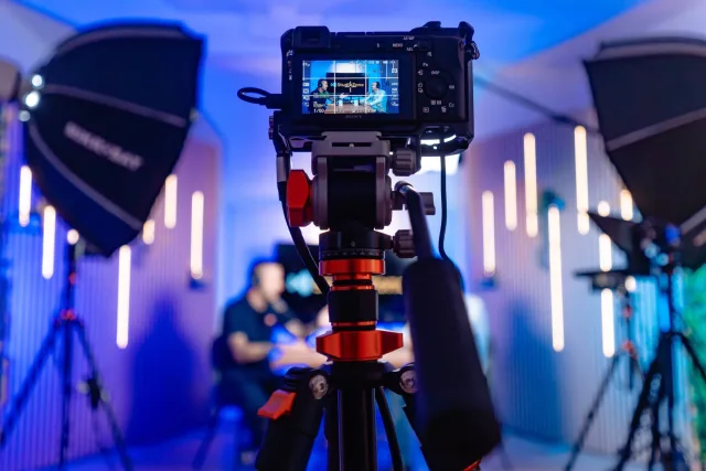 Sony kamera állványon a Zóne stúdióban, LED-es faléces fal, háttérben a vendégek