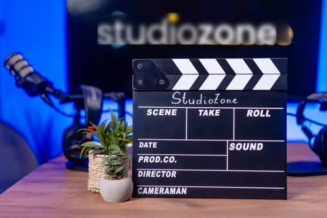 StudioZone feliratú csapó és kis növény a videó stúdió asztalán, neon logóval