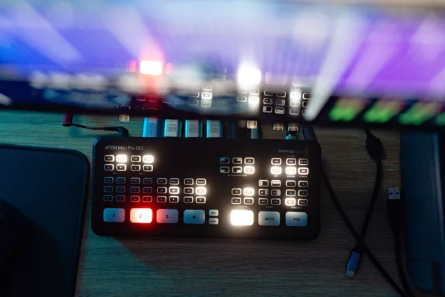 ATEM Mini Pro ISO videókeverő közeli képe világító gombokkal, kék fényben