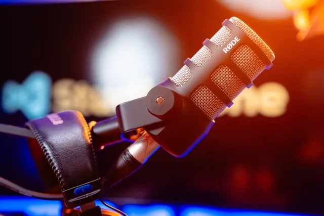 Rode mikrofon és fejhallgató közeli képe meleg hátsó fénnyel a podcast stúdióban